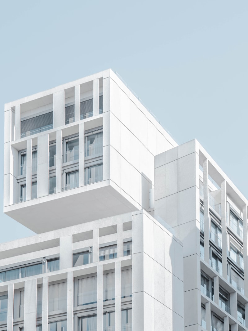 Cantilevered upper floors of a pale concrete building against a clear sky